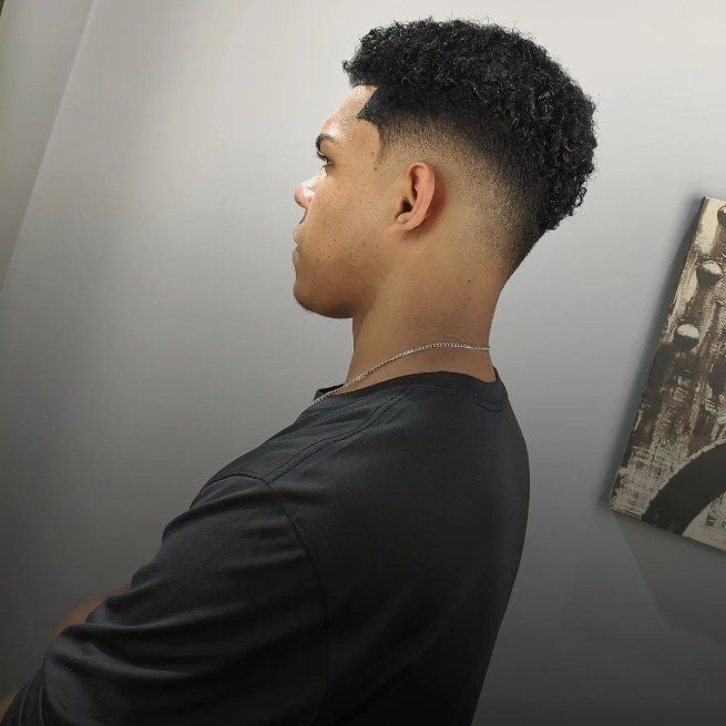 Corte cacheado de perfil, com degradê